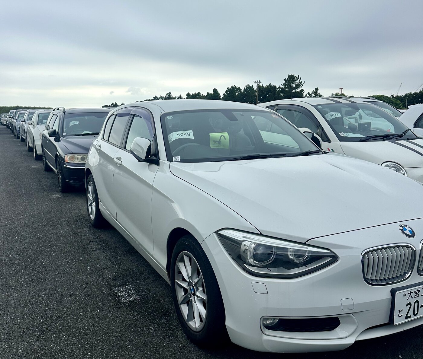 White BMW parked beside rows of used cars