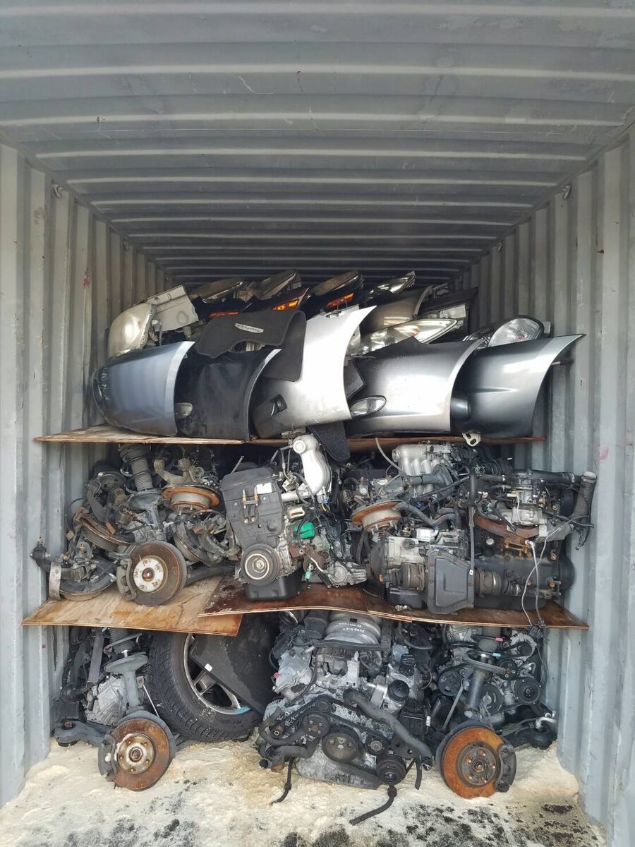Body panels above engines on a wooden shelf inside a container