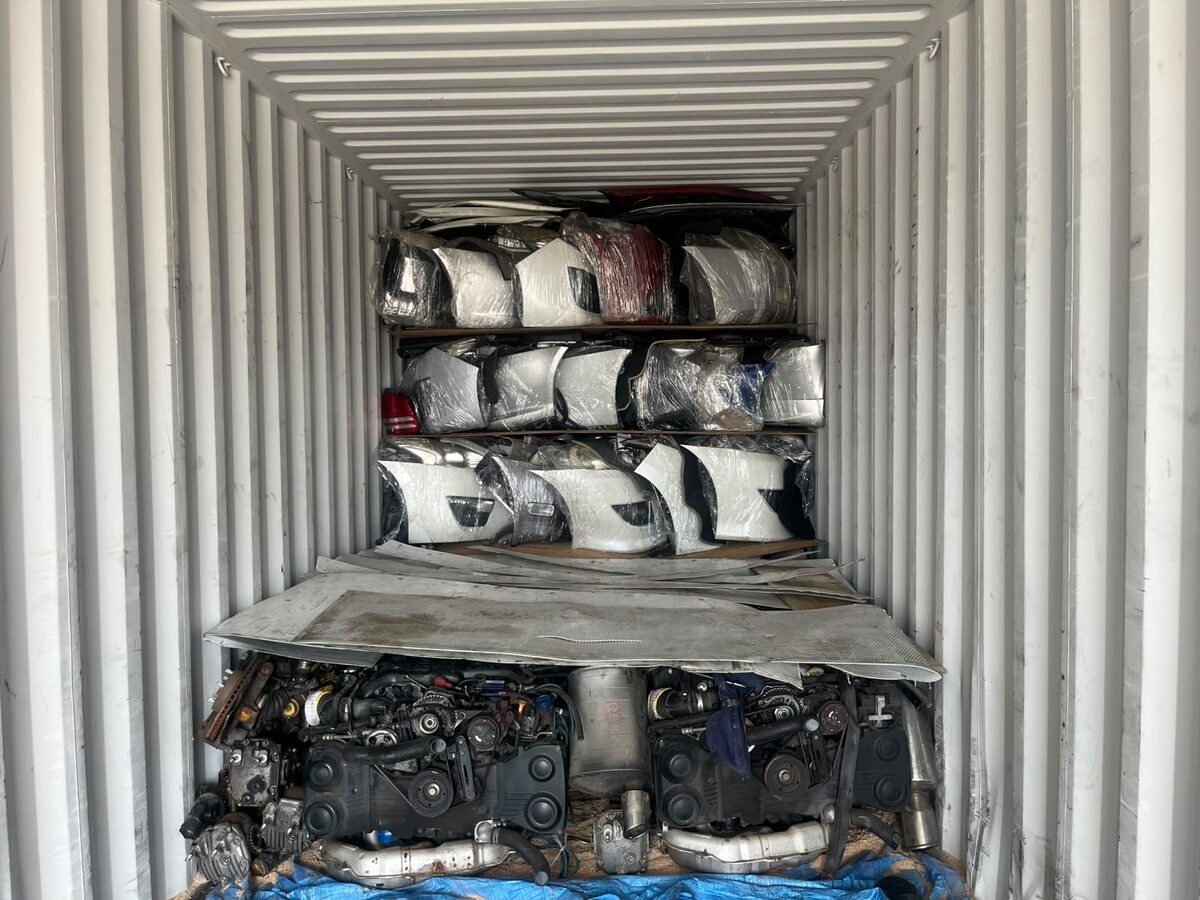 Vehicle body panels stacked above engines inside a shipping container