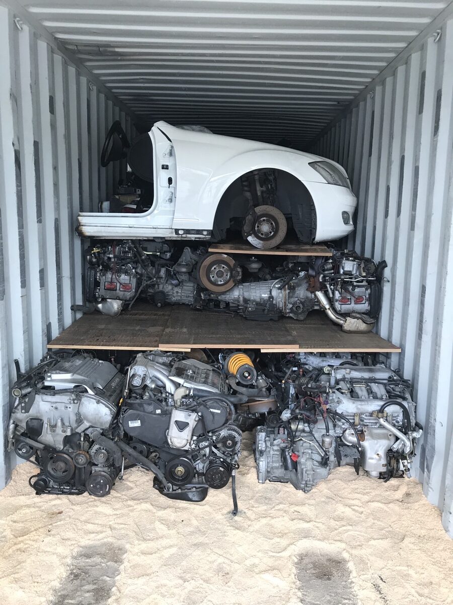 White vehicle front section and rows of engines at the back of a container