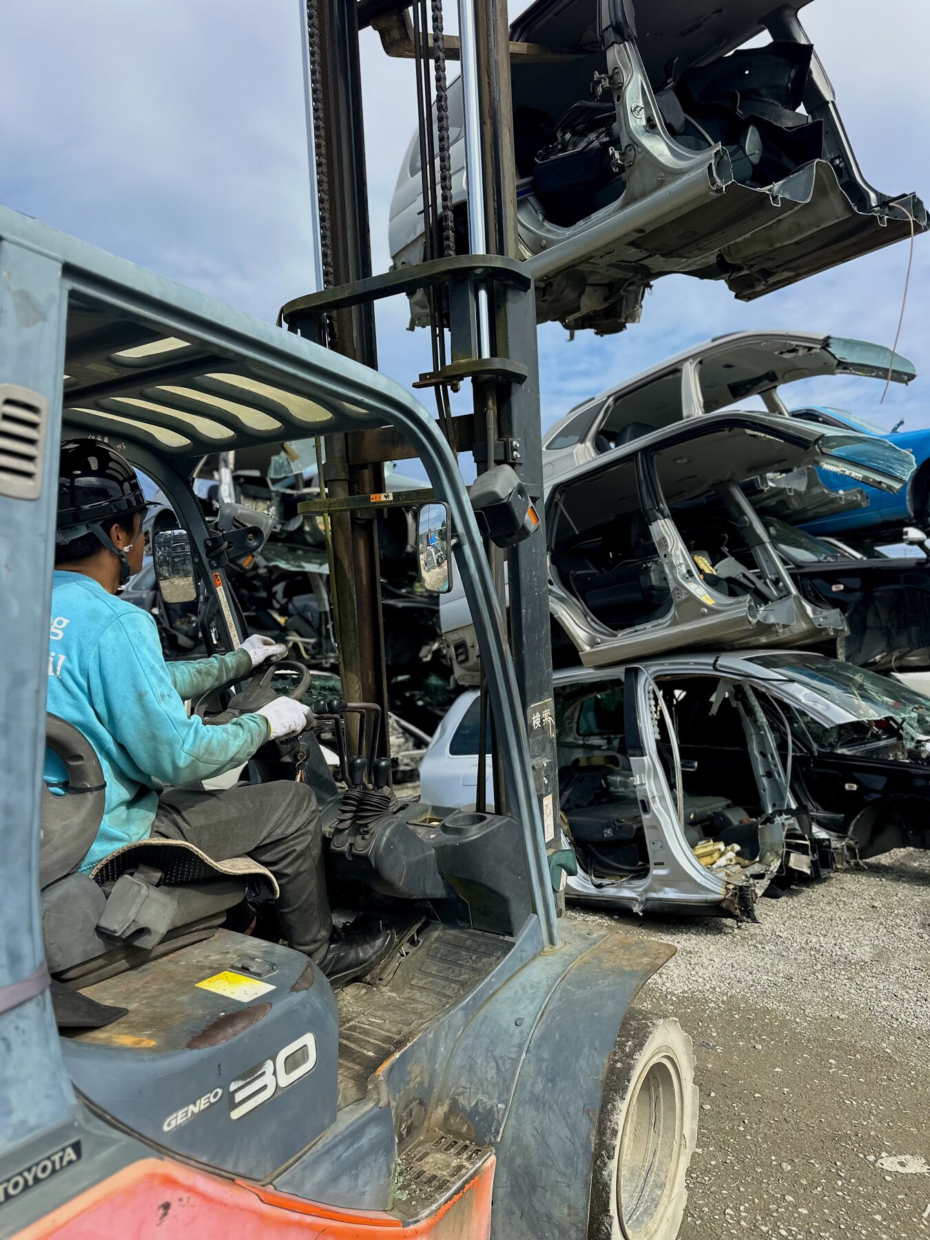 Worker beside a forklift and racks of used engines