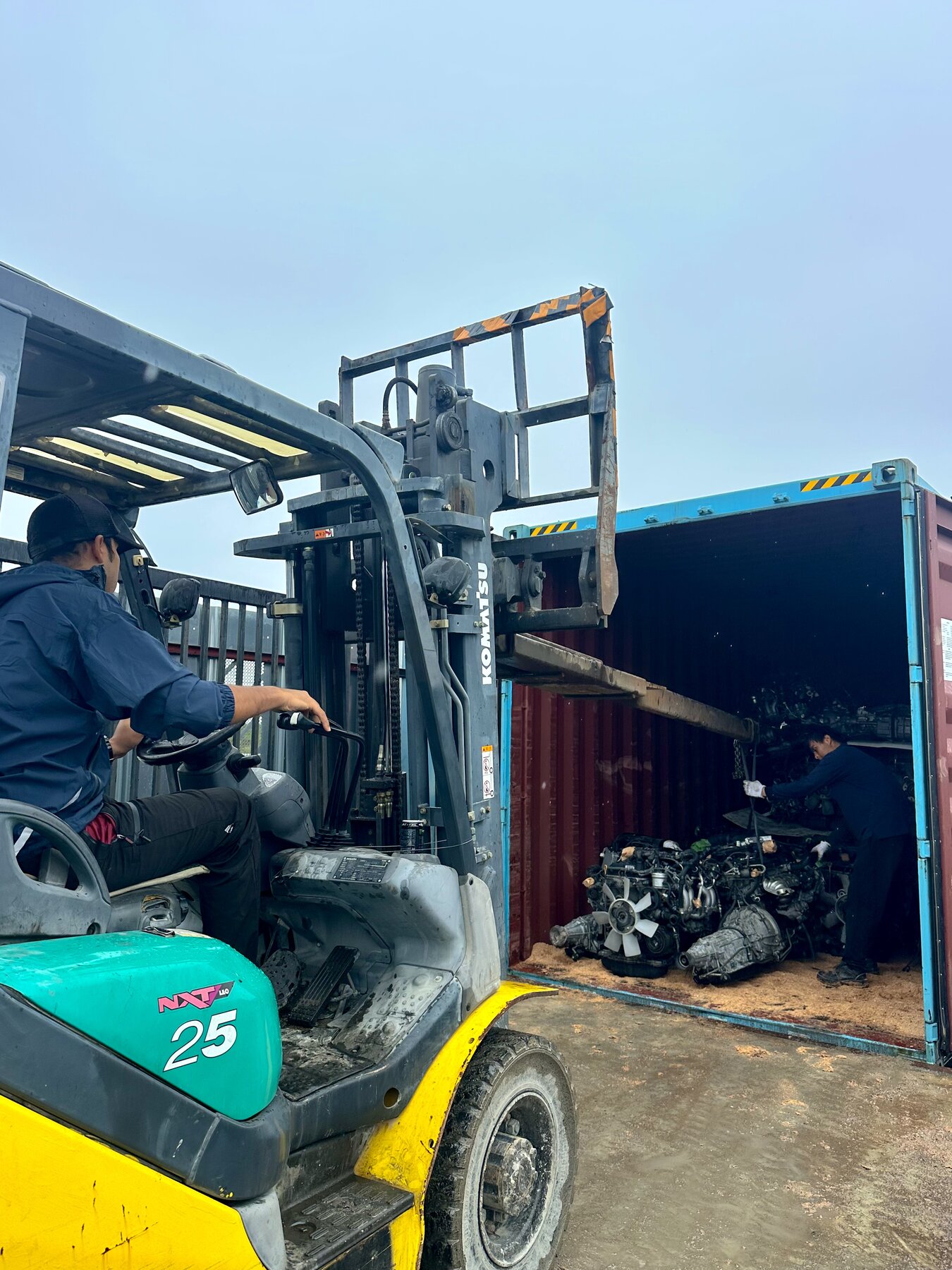 Forklift beside an open shipping container in the yard