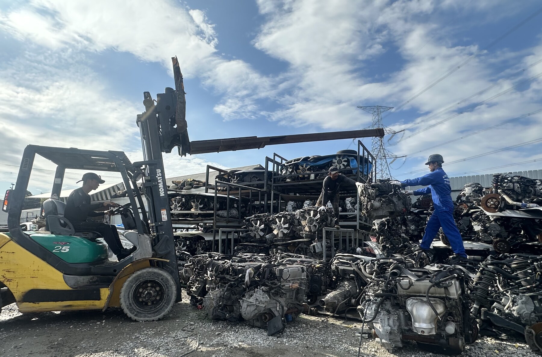 Forklift and workers among engine racks in the yard