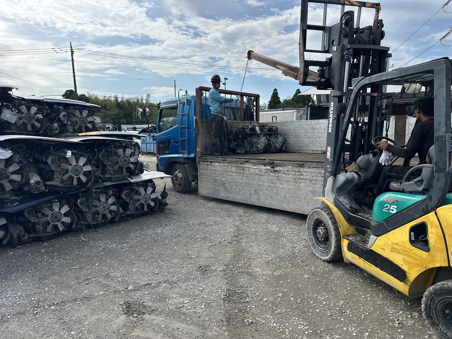 Forklift moving beside racks of used engines