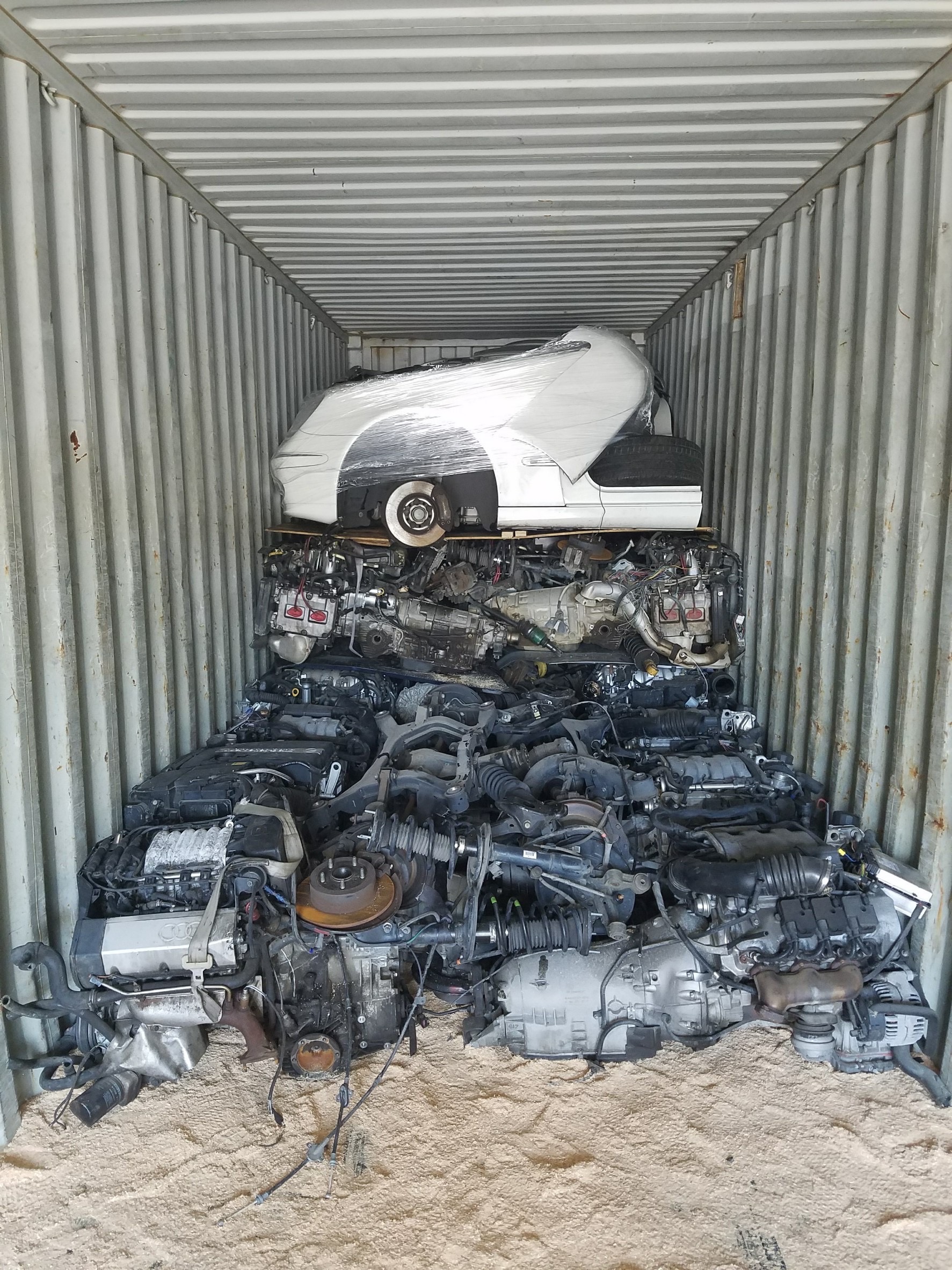 Used engines and a dismantled car body stacked inside a shipping container